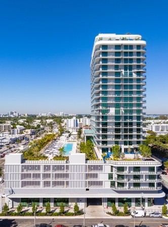 Aerial view of the PALMA Miami Beach tower rising above North Beach under a clear blue sky