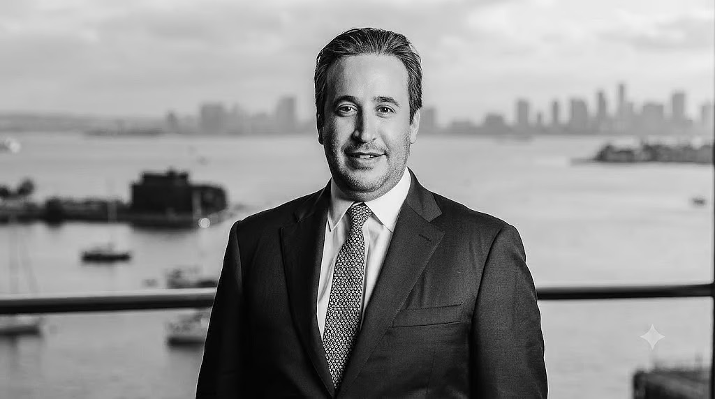 Black-and-white portrait of Mendy Chudaitov with the Miami skyline and bay behind him