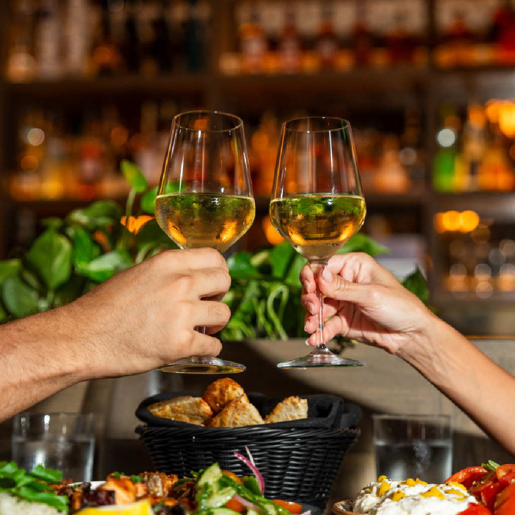 two people clinking with wine glasses in a restaurant